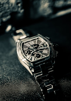 A cartier watch lies on a textured surface.