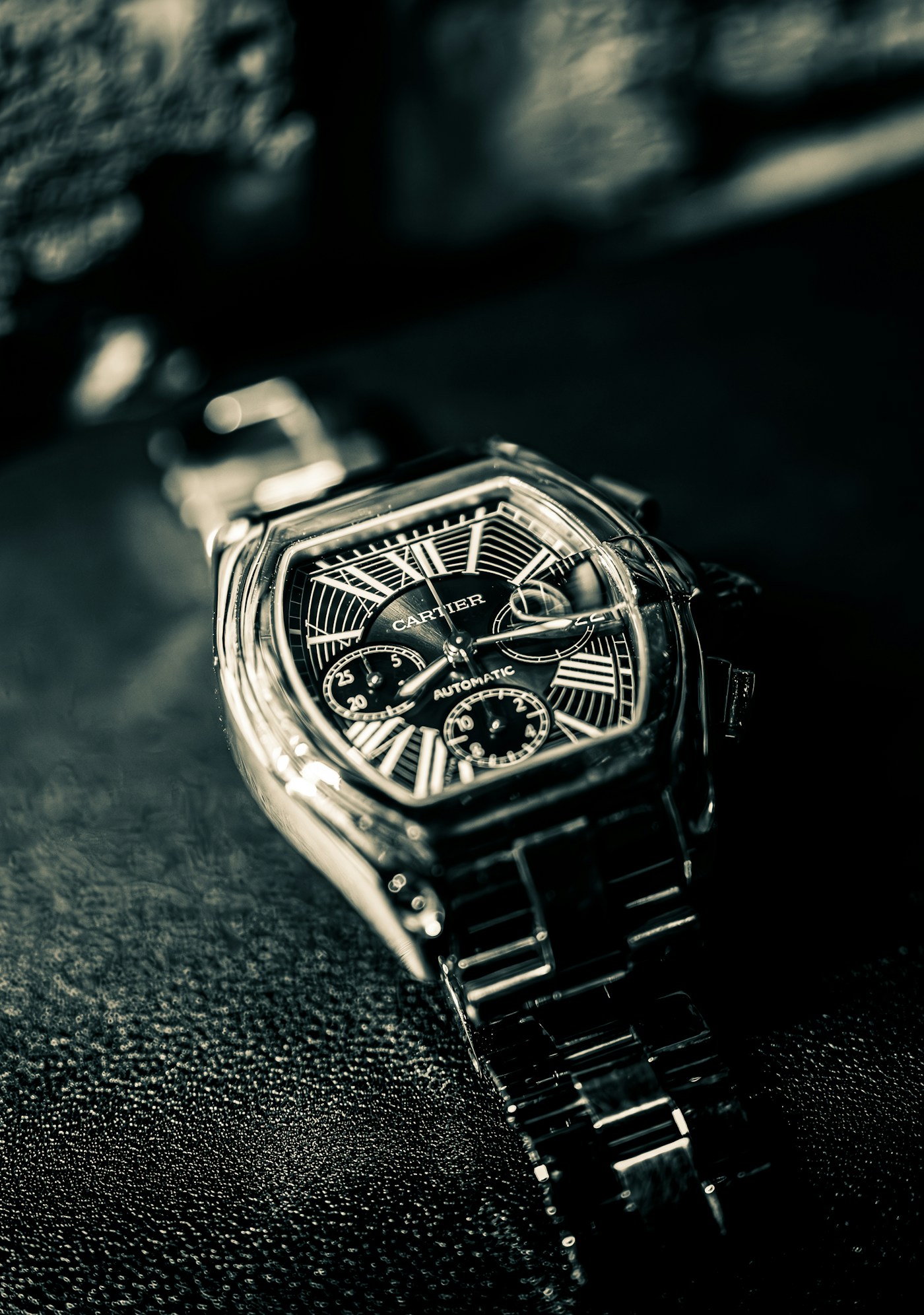 Cartier Roadster chronograph watch on dark textured surface for auction