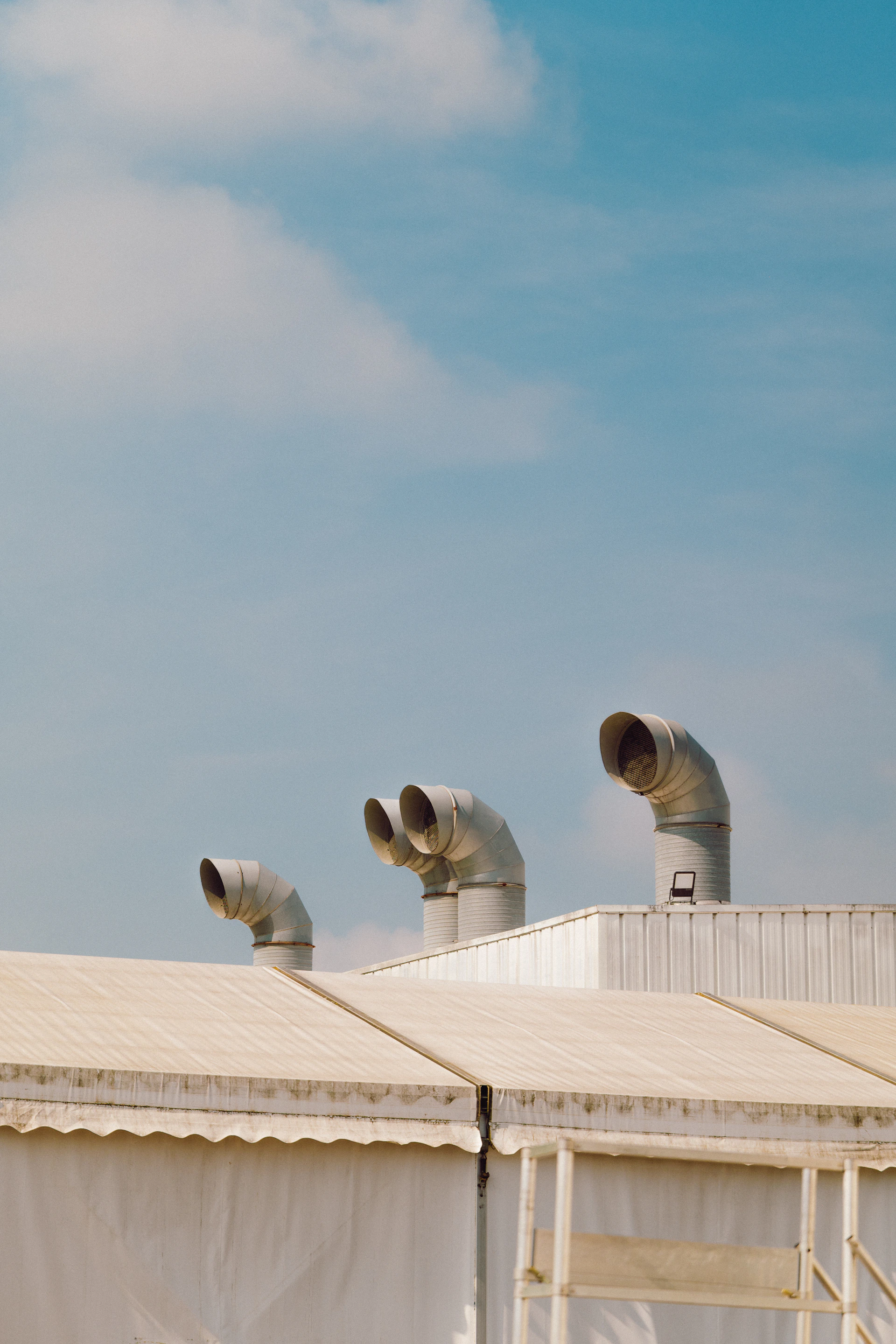 Industrial pipes sit atop a white building.