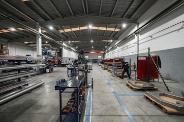 Inside a large factory, equipment and workers are present.