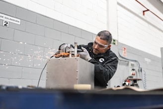 A worker uses a grinder, creating sparks.