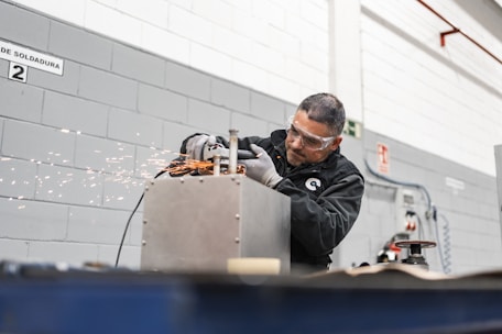 A worker uses a grinder, creating sparks.