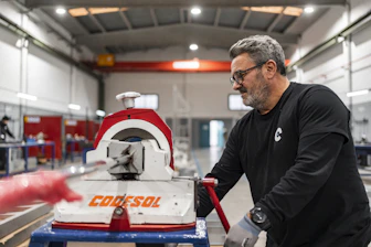 A man operates industrial machinery in a workshop.