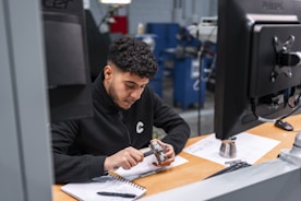 A man measures a metal component carefully.