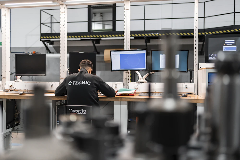 Technician working at several computer screens in an industrial plant