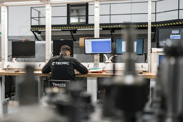 Técnico frente a varios monitores en una estación de trabajo de planta, revisando documentos y planos, contexto de la agencia de marketing digital para industria