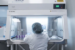 Pharmacy technician preparing compounded medications inside a sterile compounding hood.