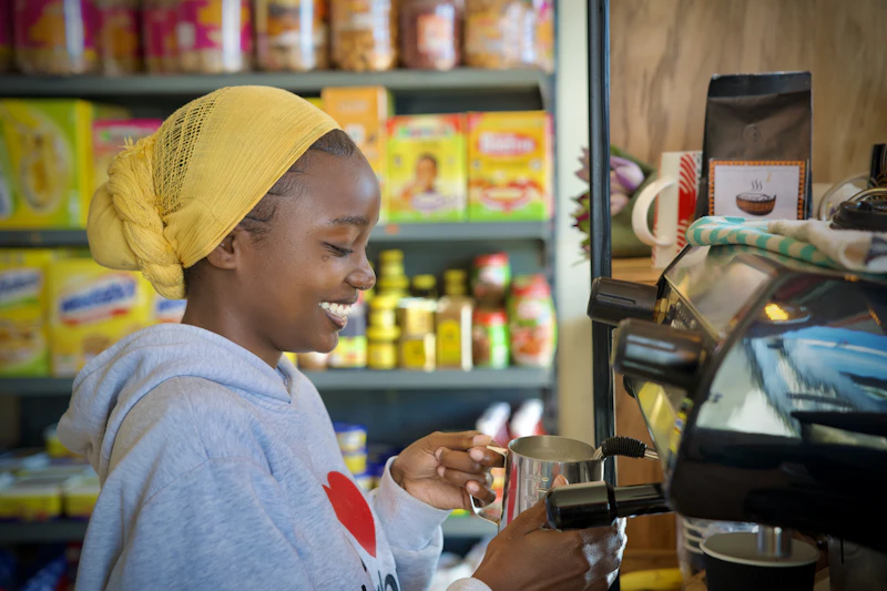 A café owner smiling while steaming milk at an espresso machine