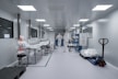 Workers in protective suits inside a sterile laboratory.