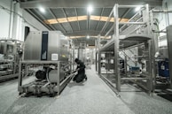 A worker repairs machinery in a factory setting.