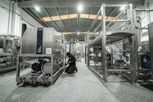 A worker repairs machinery in a factory setting.