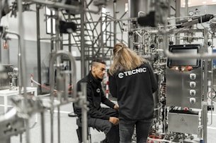 Two people work on complex industrial equipment.