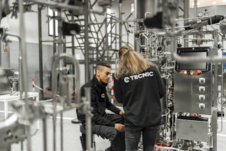Two people work on complex industrial equipment.