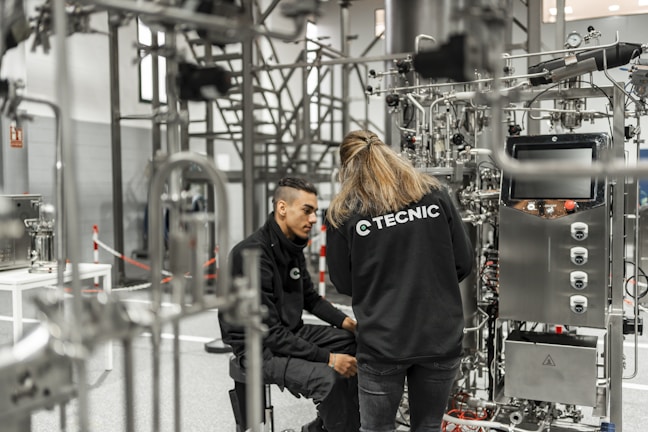 Two people work on complex industrial equipment.
