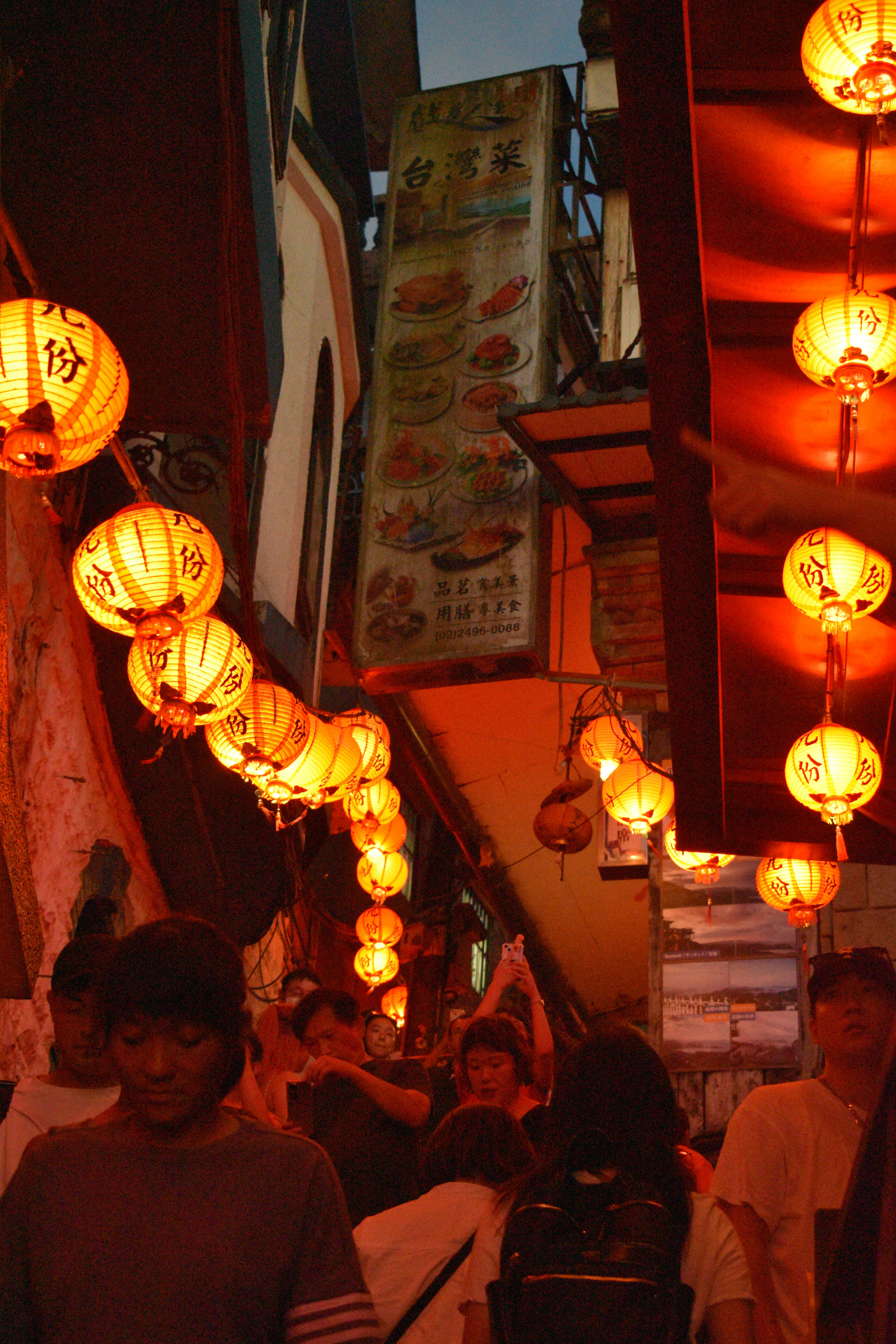 Lanterns illuminate a crowded alleyway.
