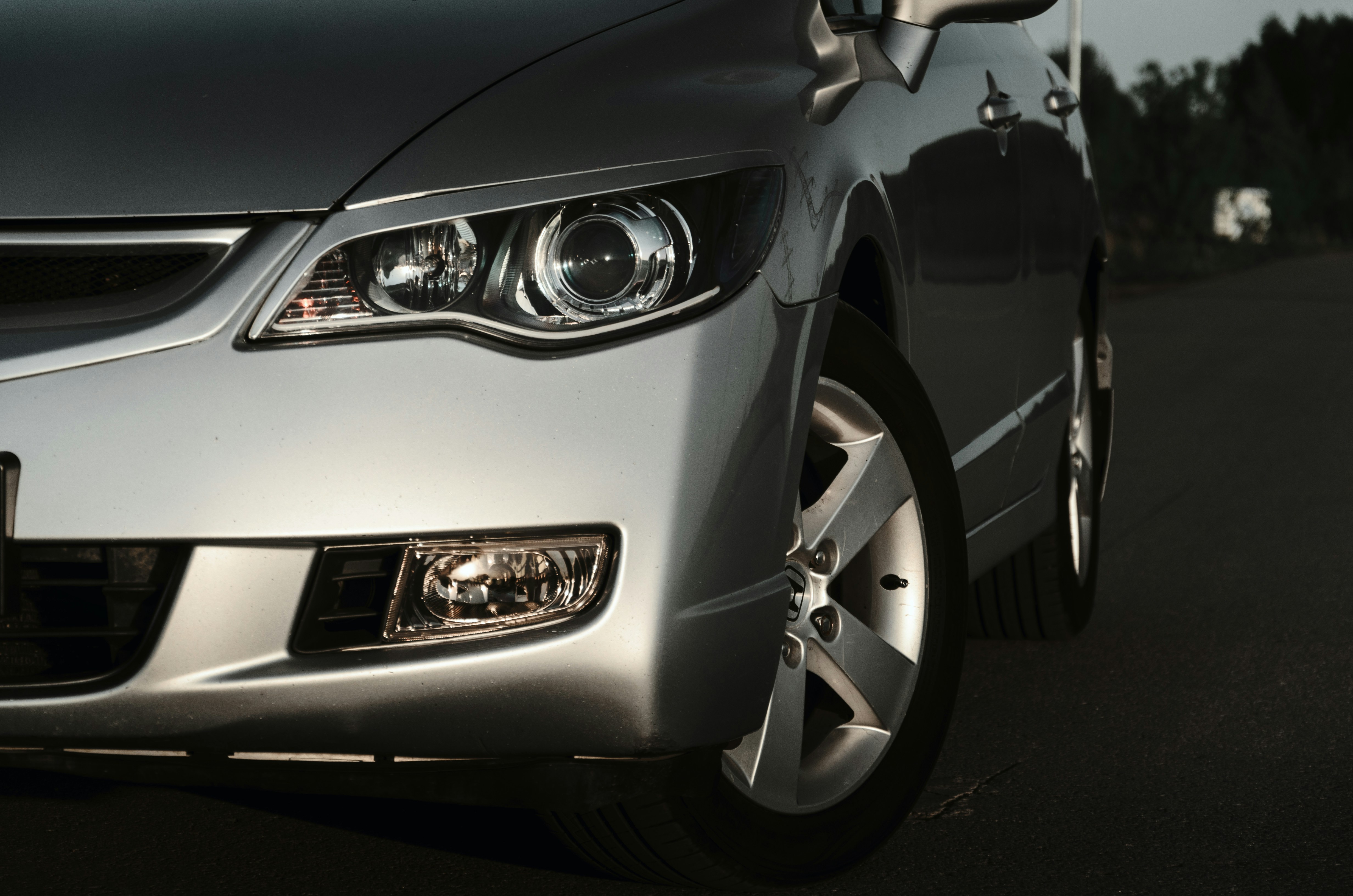 Here is a possible caption: a silver car's headlight is in focus.