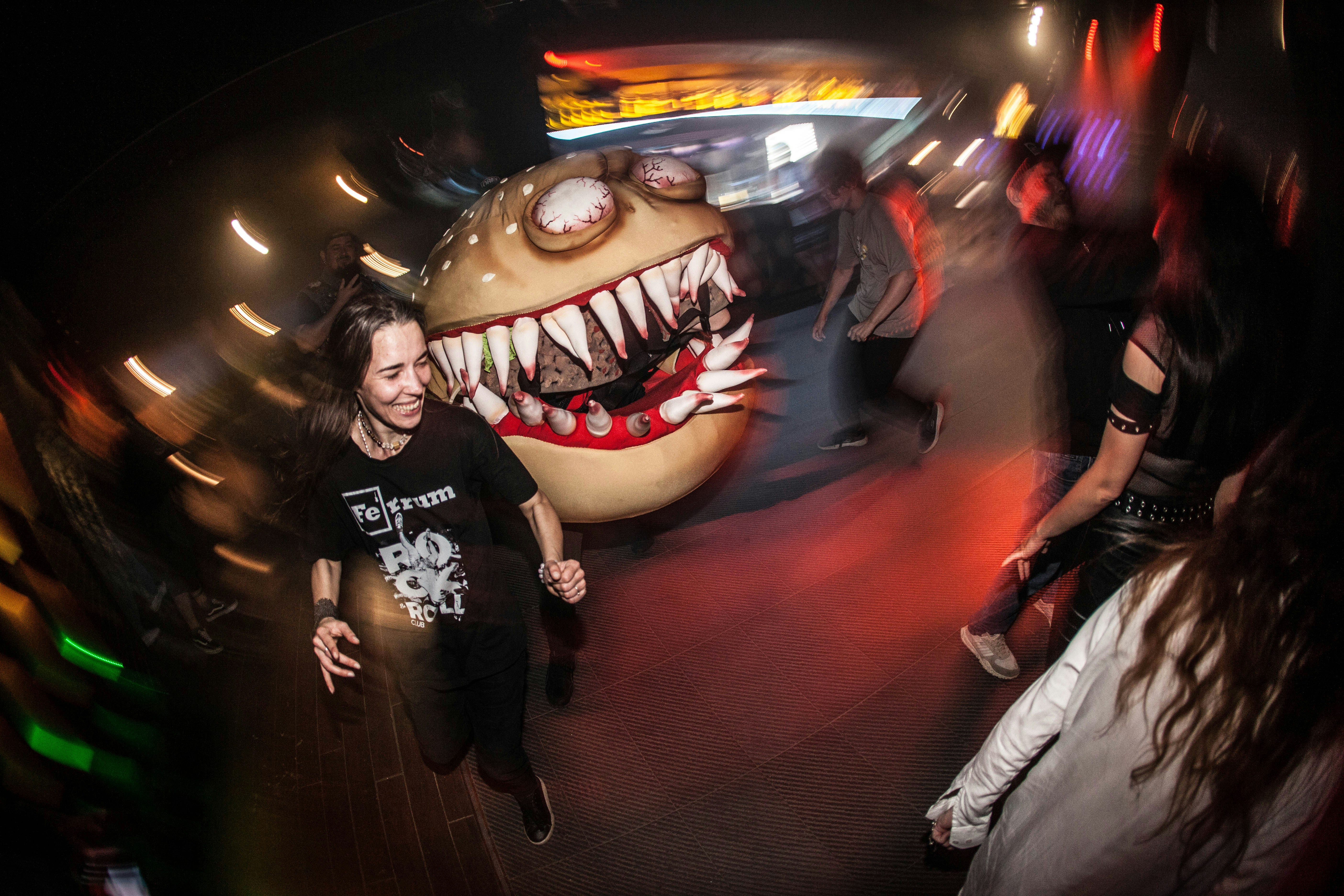 People run from a giant, scary monster in a club.