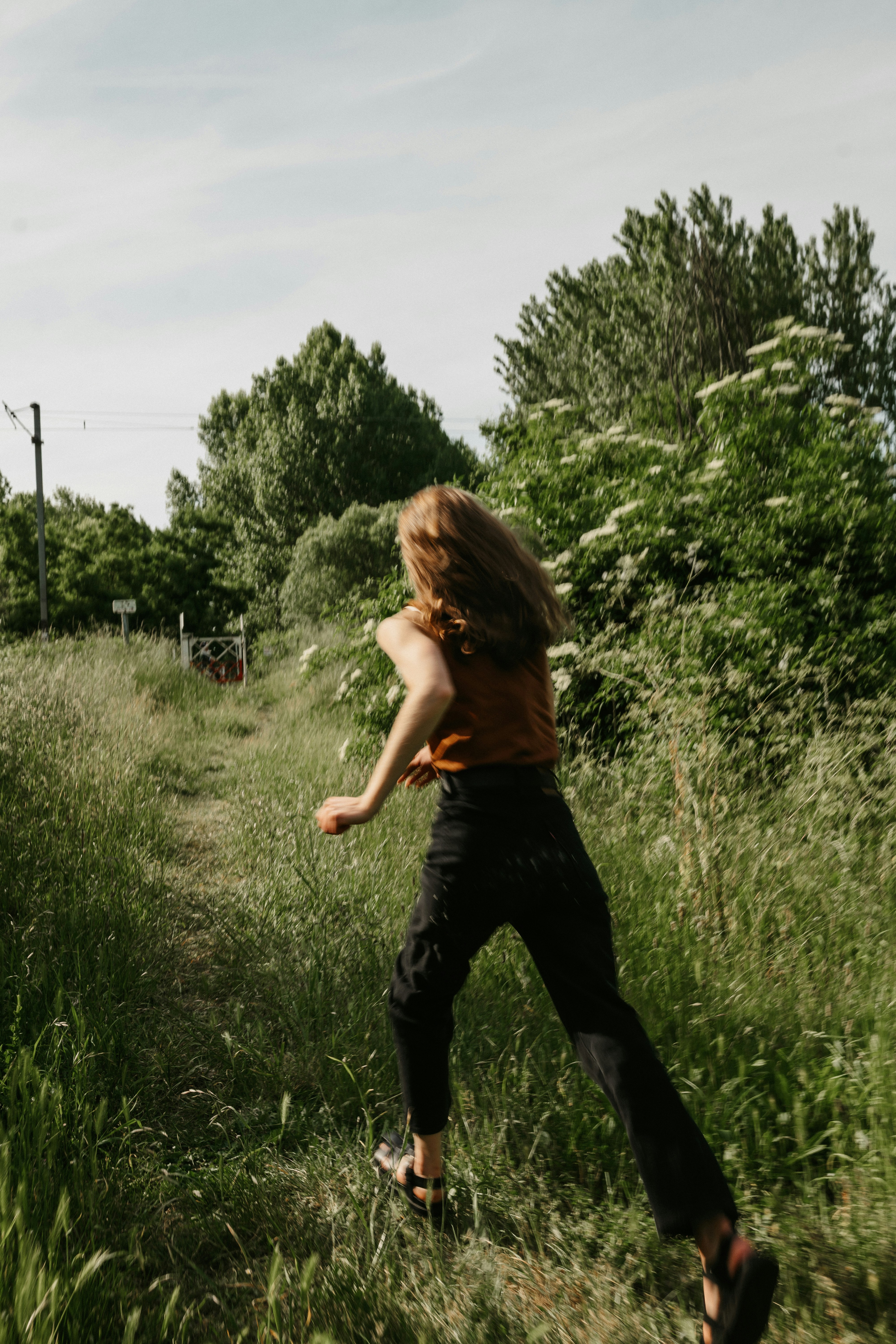 A woman runs happily down a green path.