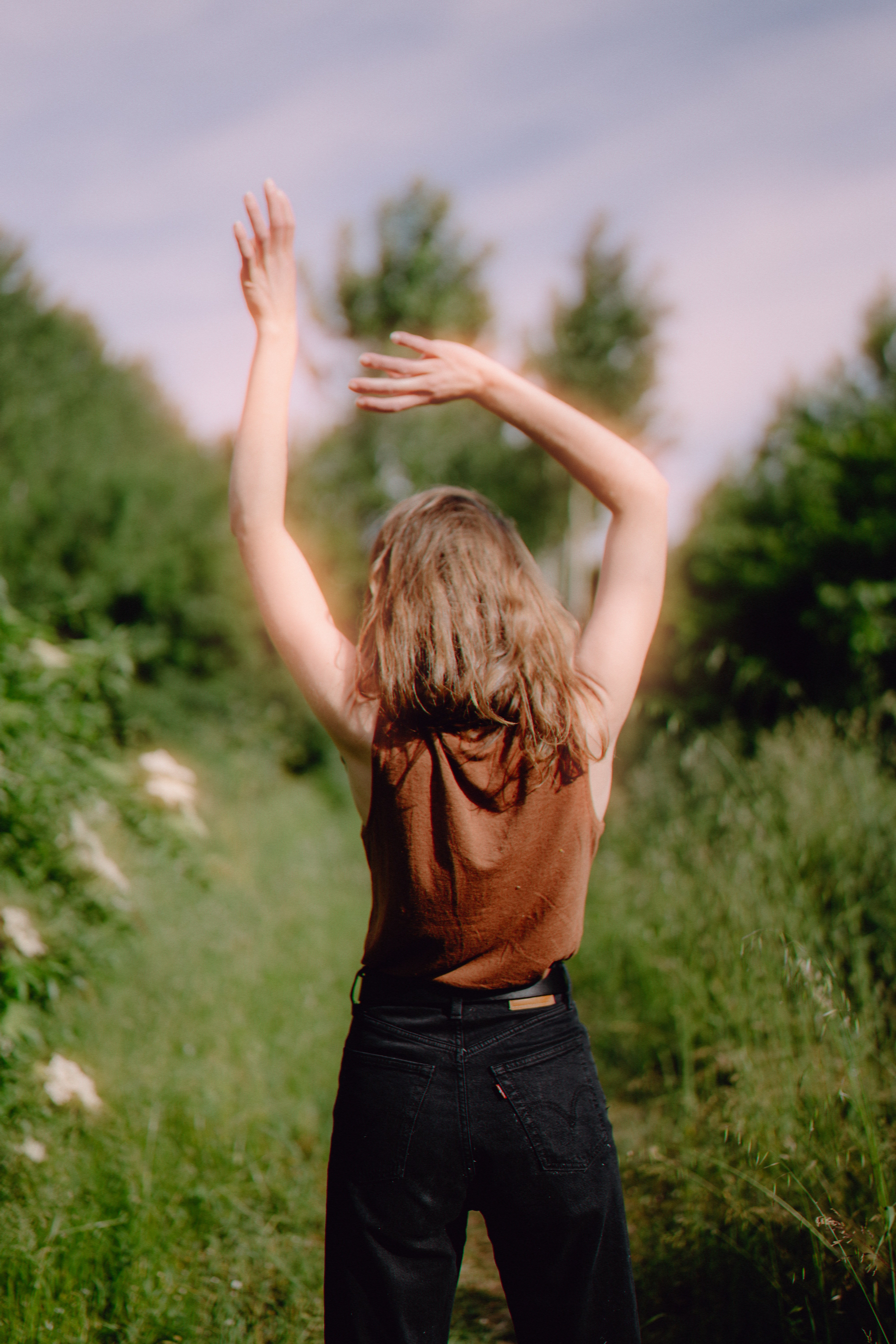 Woman raises her arms in a field.