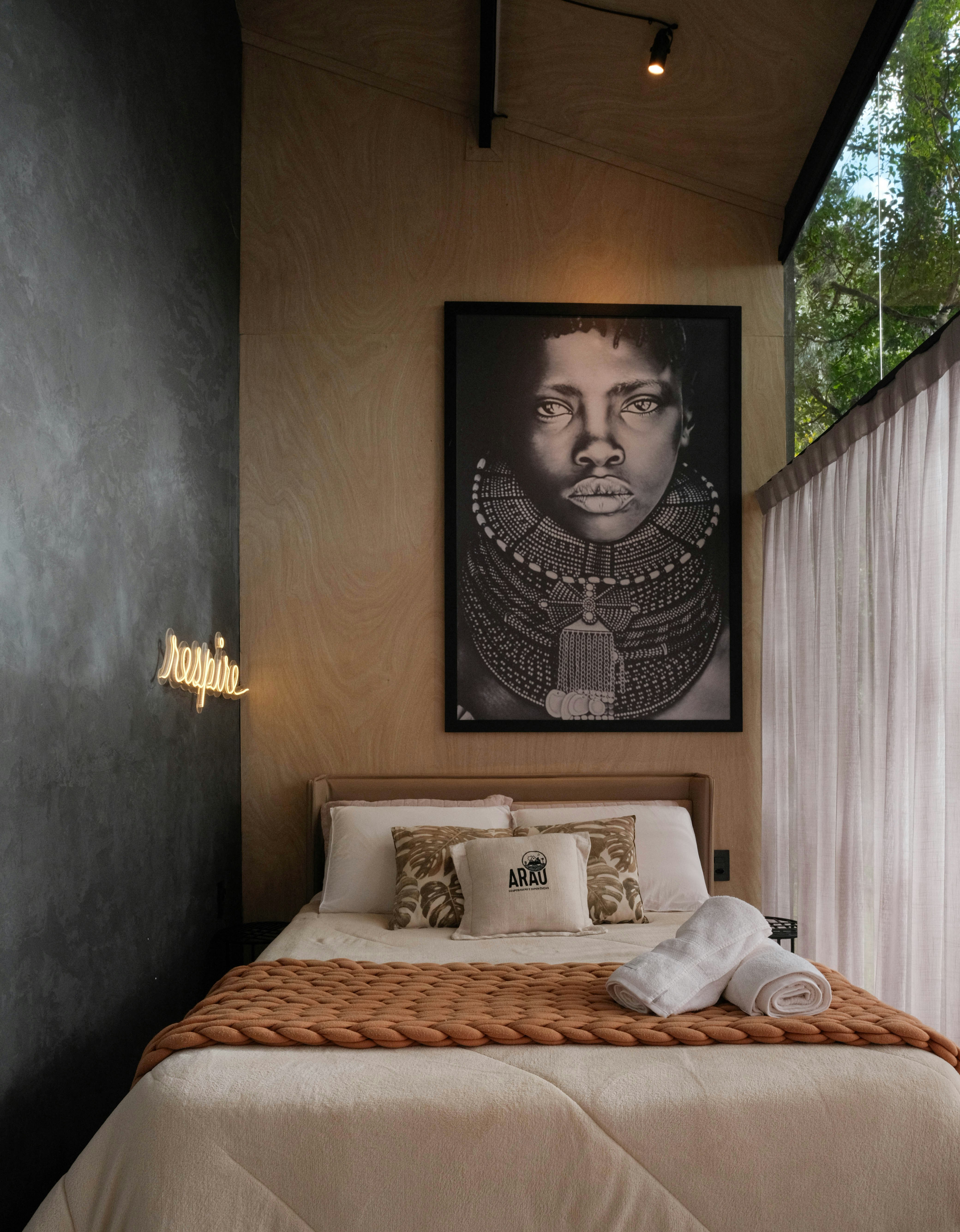 Um quarto possui um grande retrato e uma cama aconchegante.