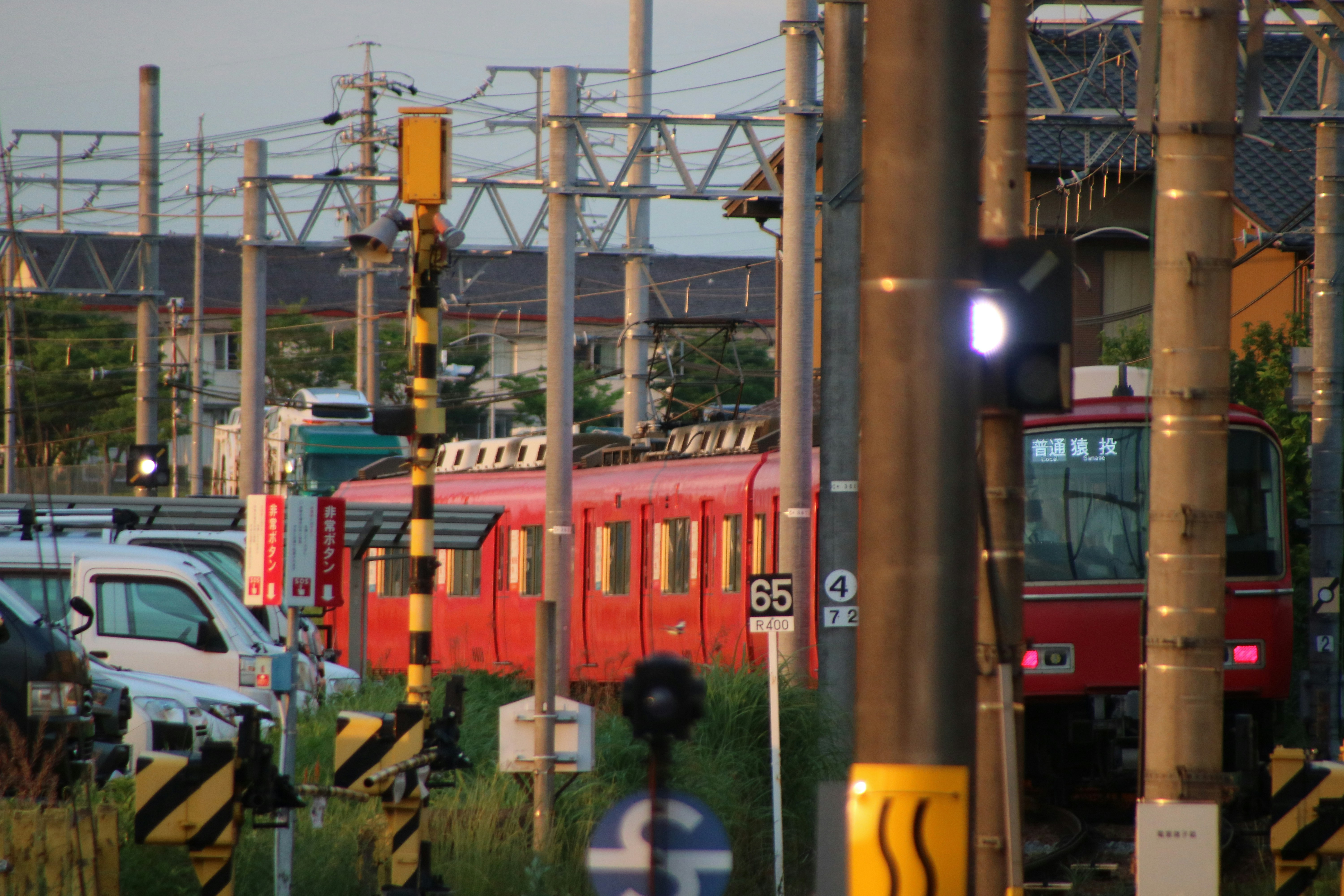 A red train is seen by a rail crossing.