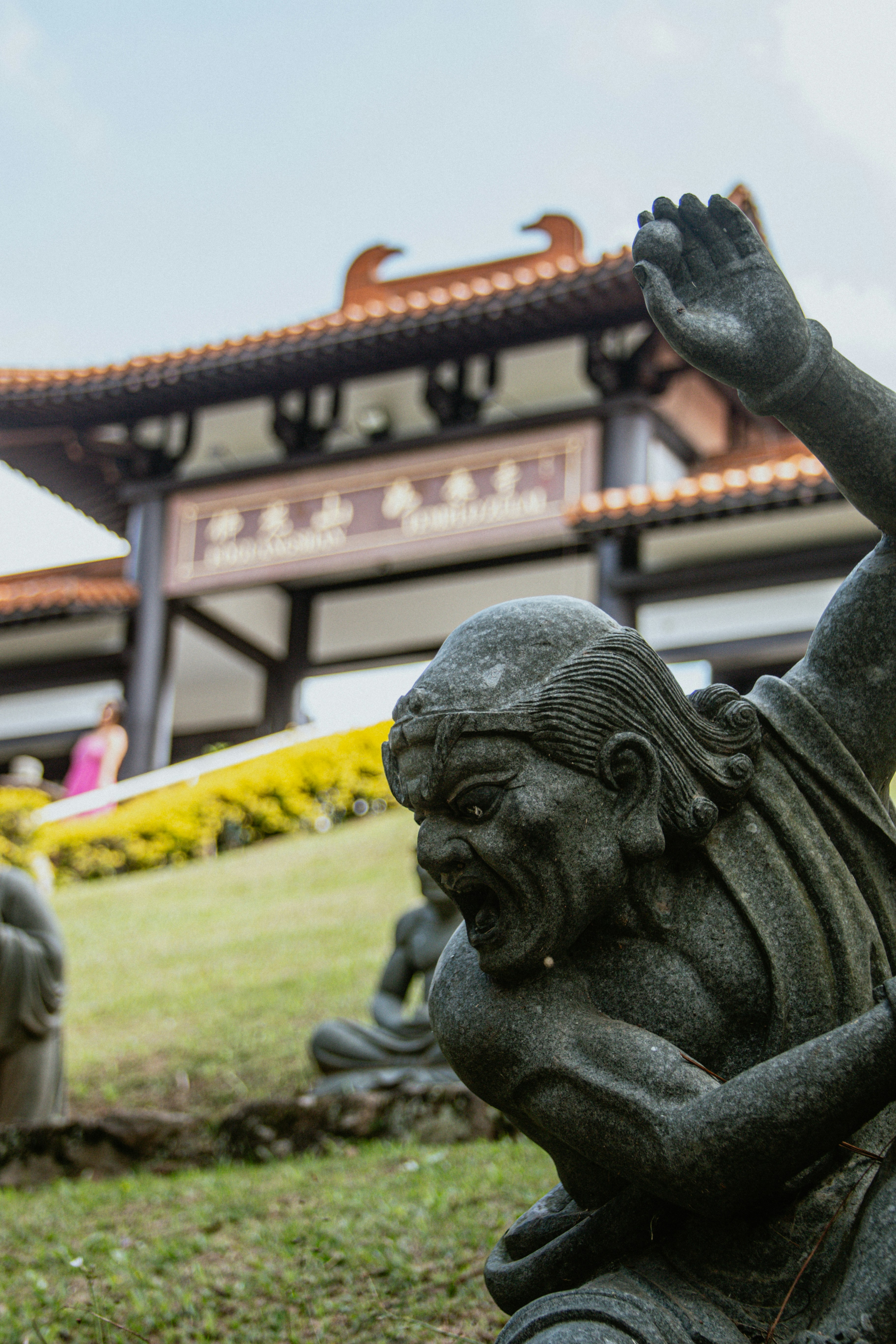 Stone statues stand before an ornate temple entrance.