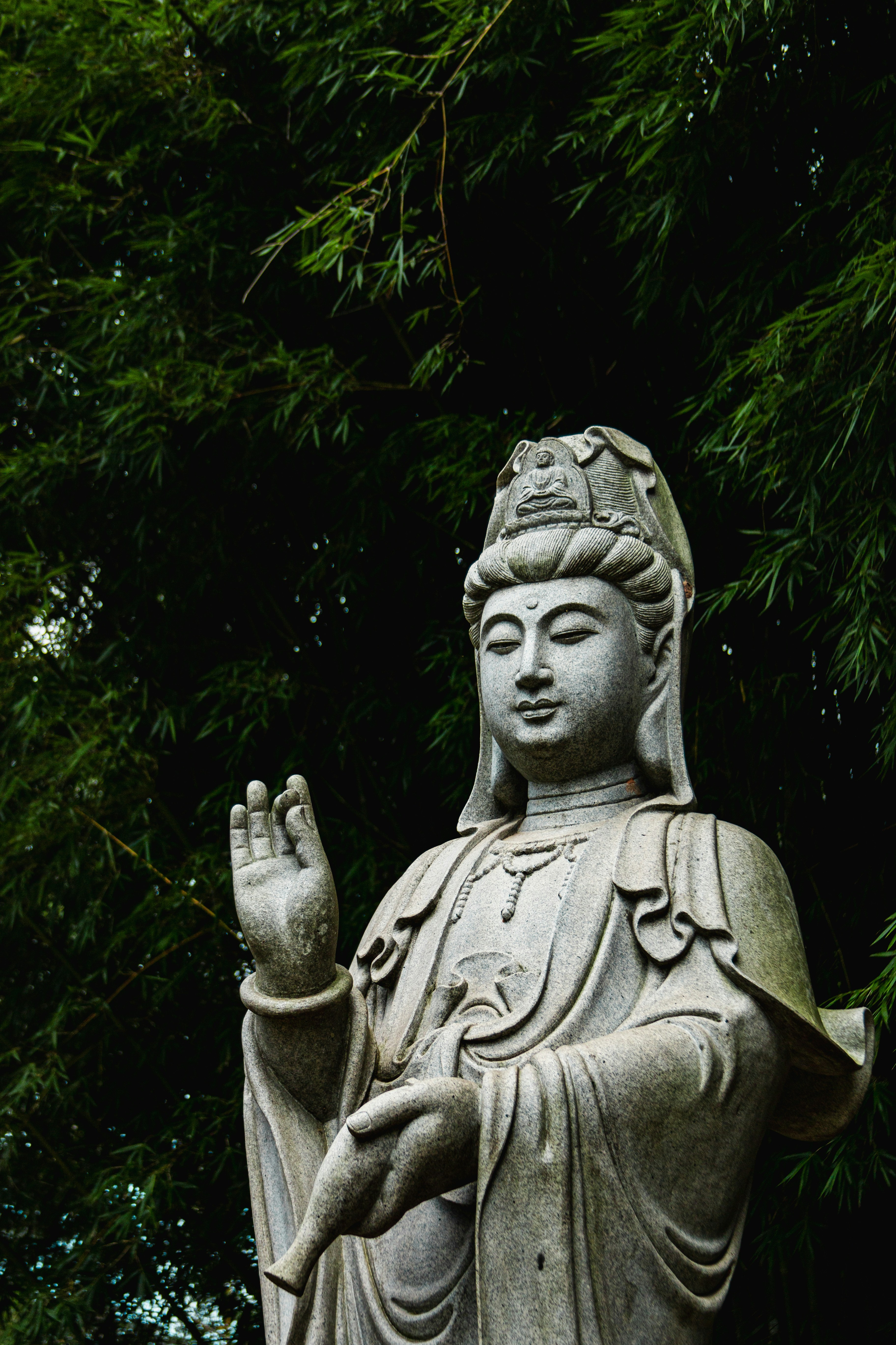 A serene stone buddha statue in a garden.
