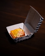 Sandwich in a striped takeout container.