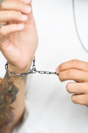 A person is fastening a silver chain bracelet.