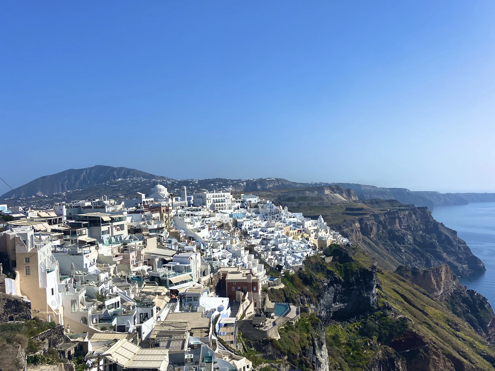 Whitewashed homes cascading down the Santorini coast above the Aegean Sea