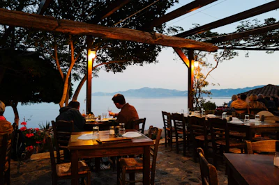 A restaurant terrace with tables set for dining, overlooking the sea