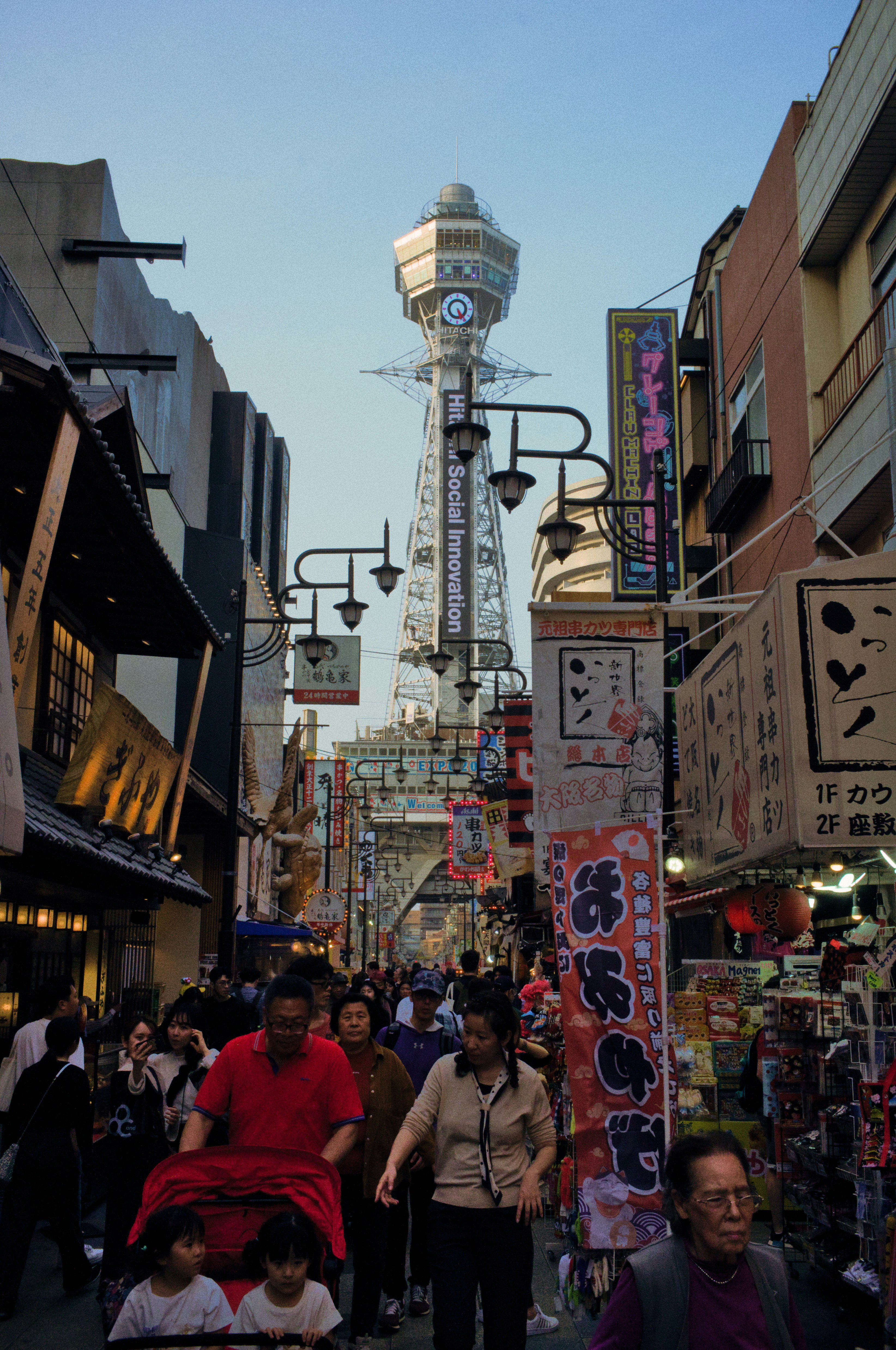 La torre tsutenkaku de Osaka se cierne sobre una calle muy transitada.