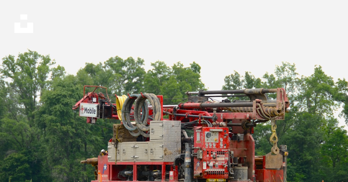 A drilling rig is set up in a grassy field. photo – Free Grass Image on ...