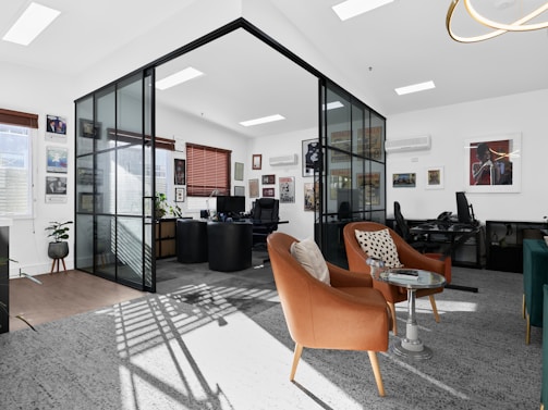 A modern office features glass walls and cozy seating.