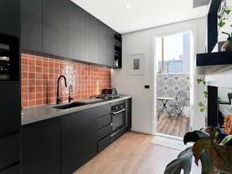 Modern kitchen has black cabinets and orange backsplash.