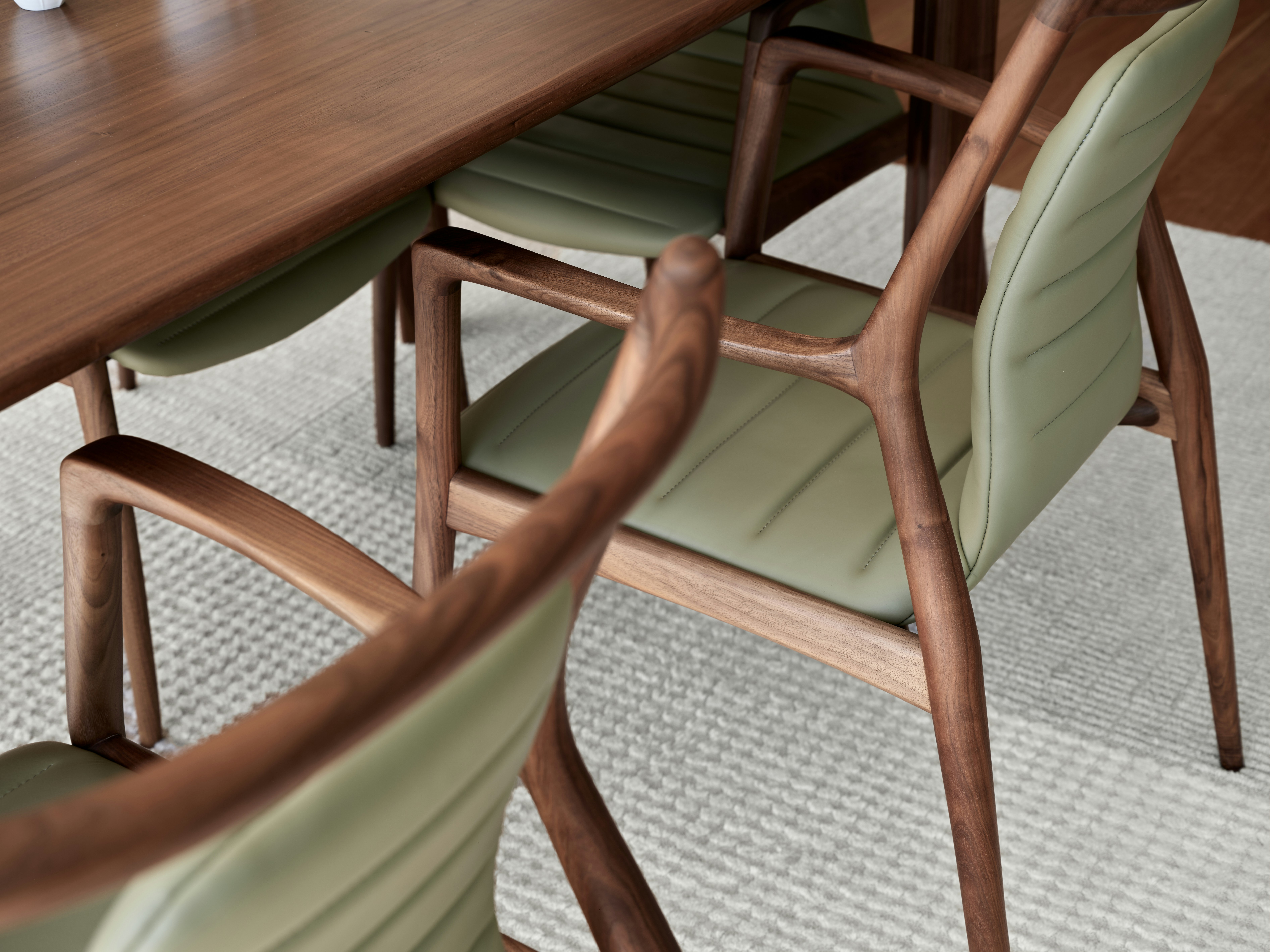 Wooden chairs with green seats surround a table.