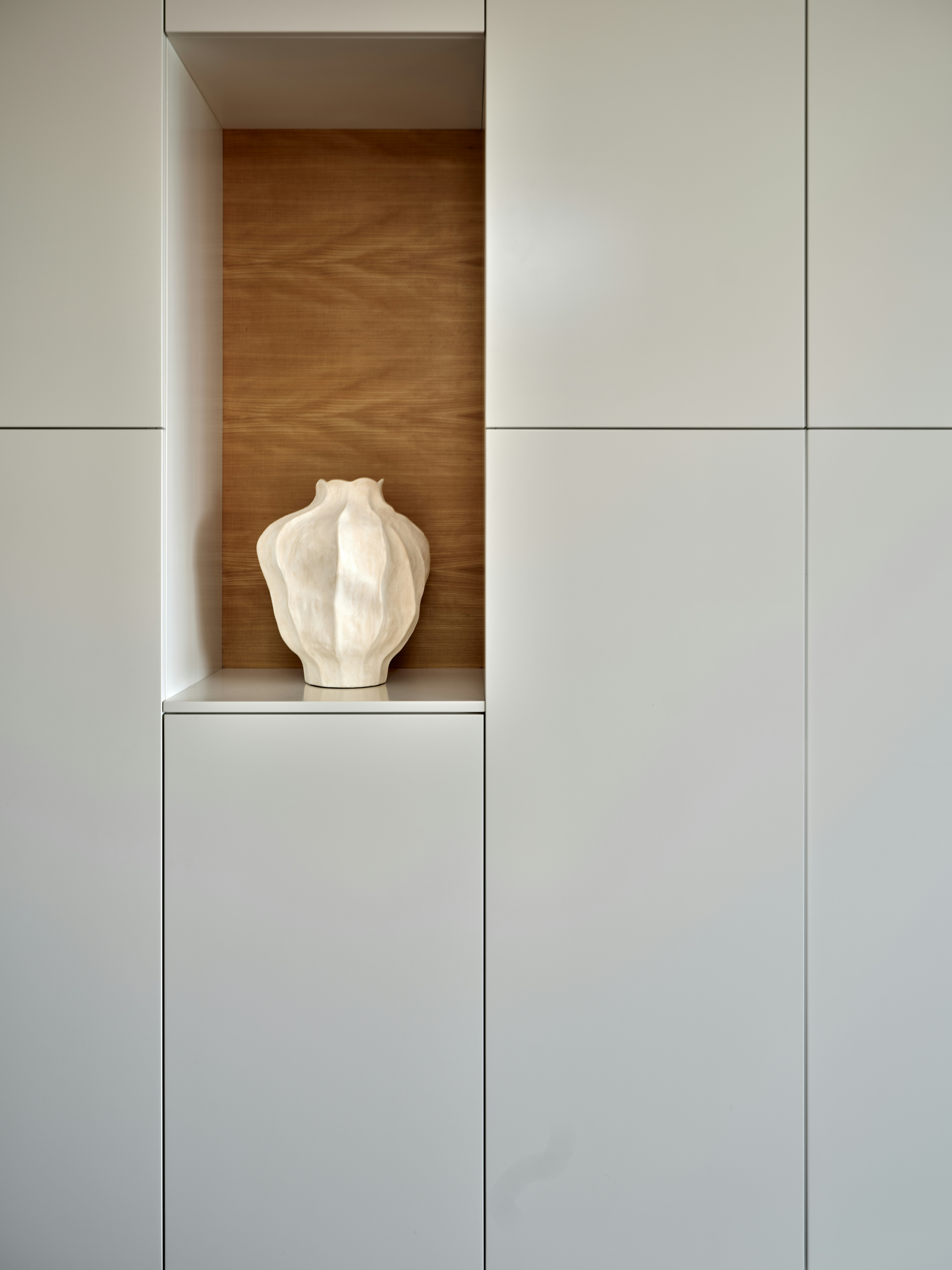 A sculptural vase sits in a built-in niche.