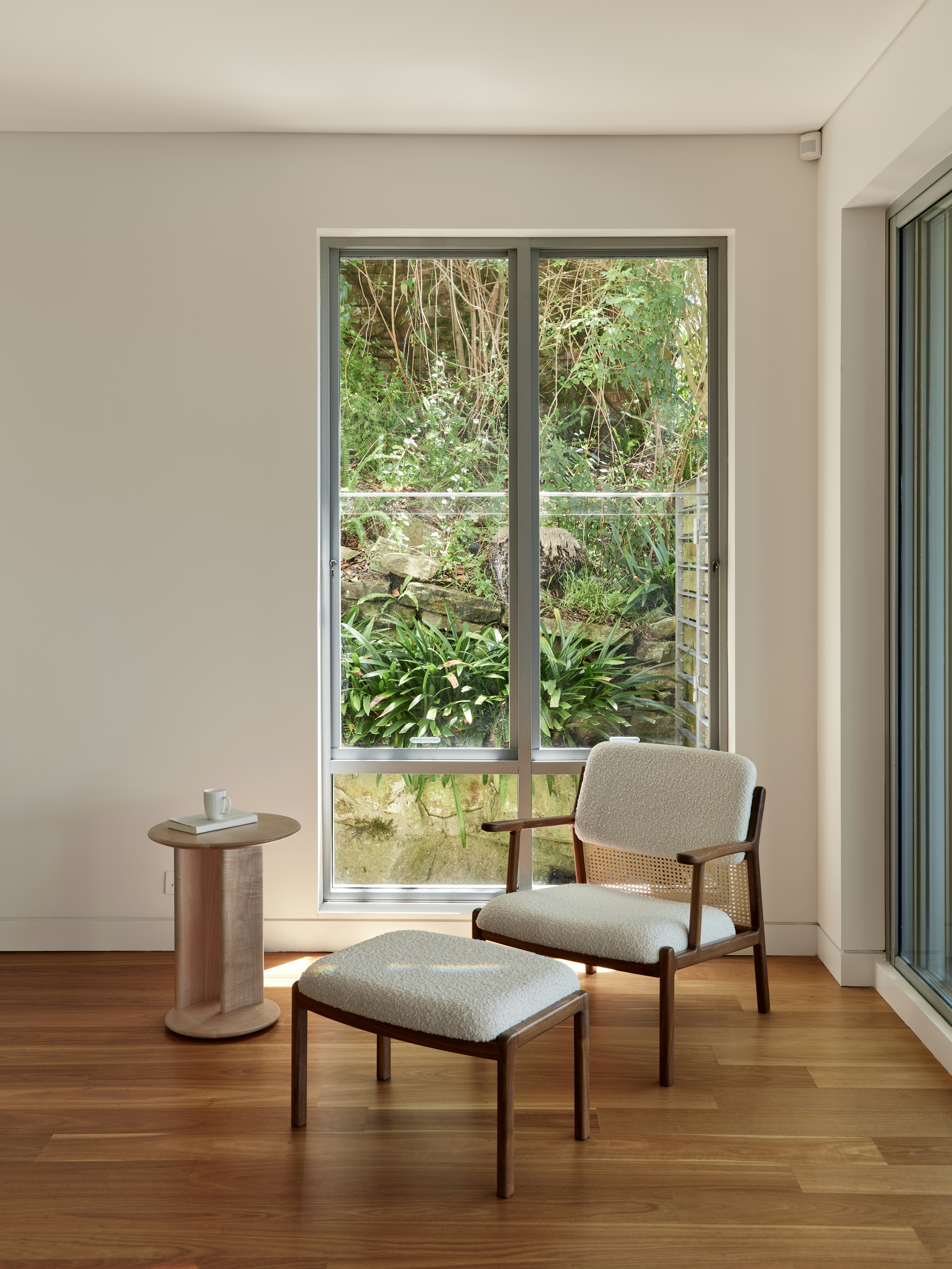 Cozy chair and ottoman sit next to a window.