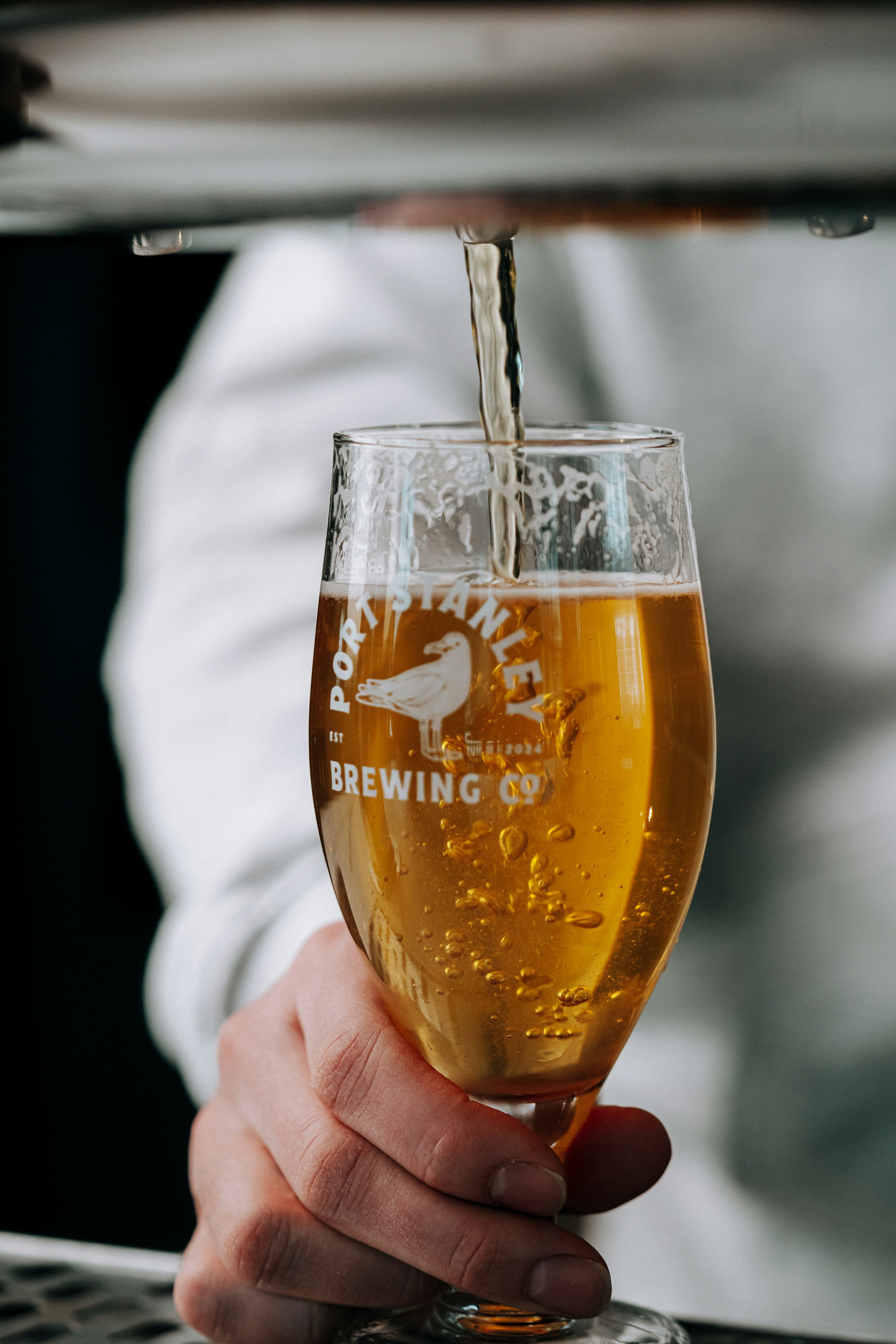 La bière est versée dans un verre de marque.