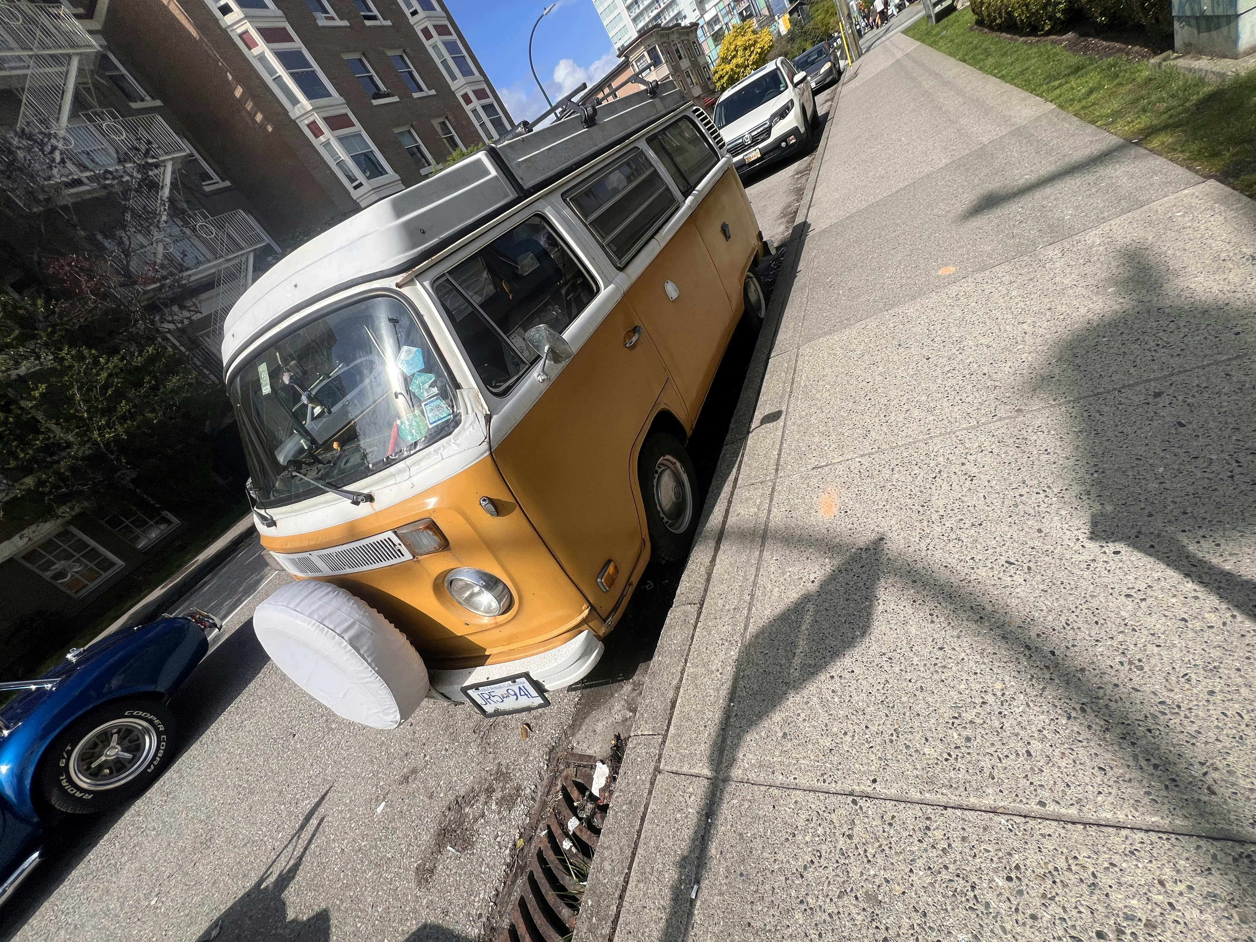 Um clássico ônibus Volkswagen amarelo está estacionado em uma rua.