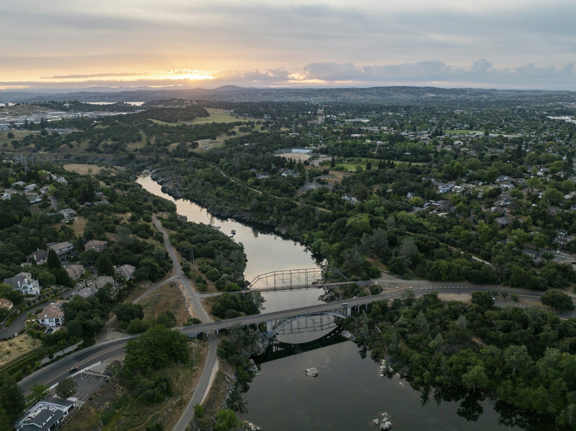 A river flows through a green landscape at sunset.