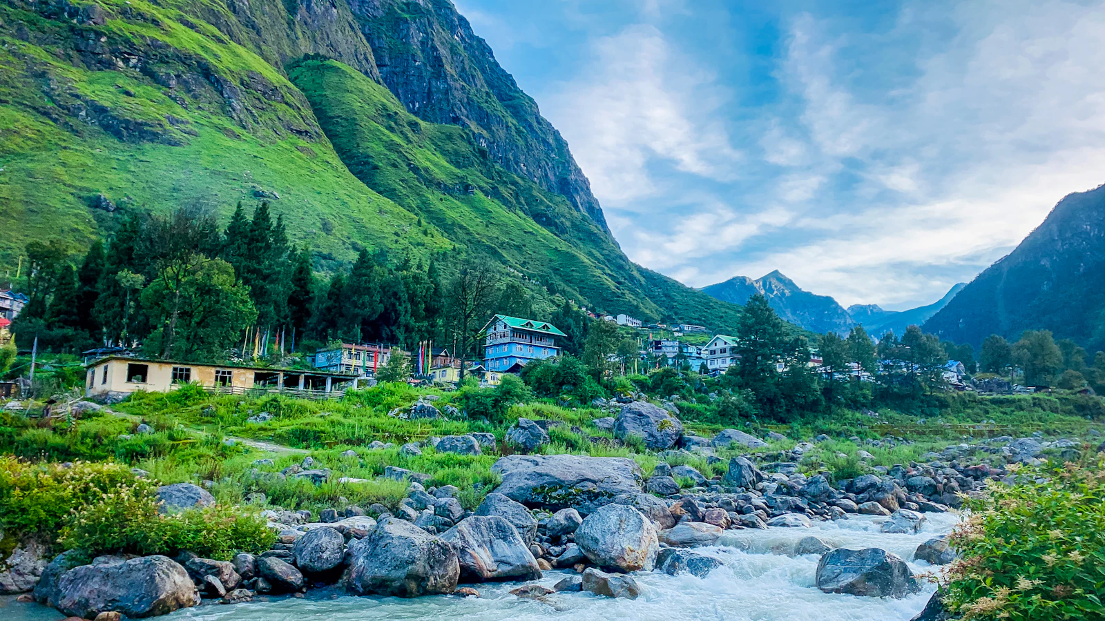 Lachung village in North Sikkim beside the boulder strewn Lachung Chu, green cliffs and a peak behind