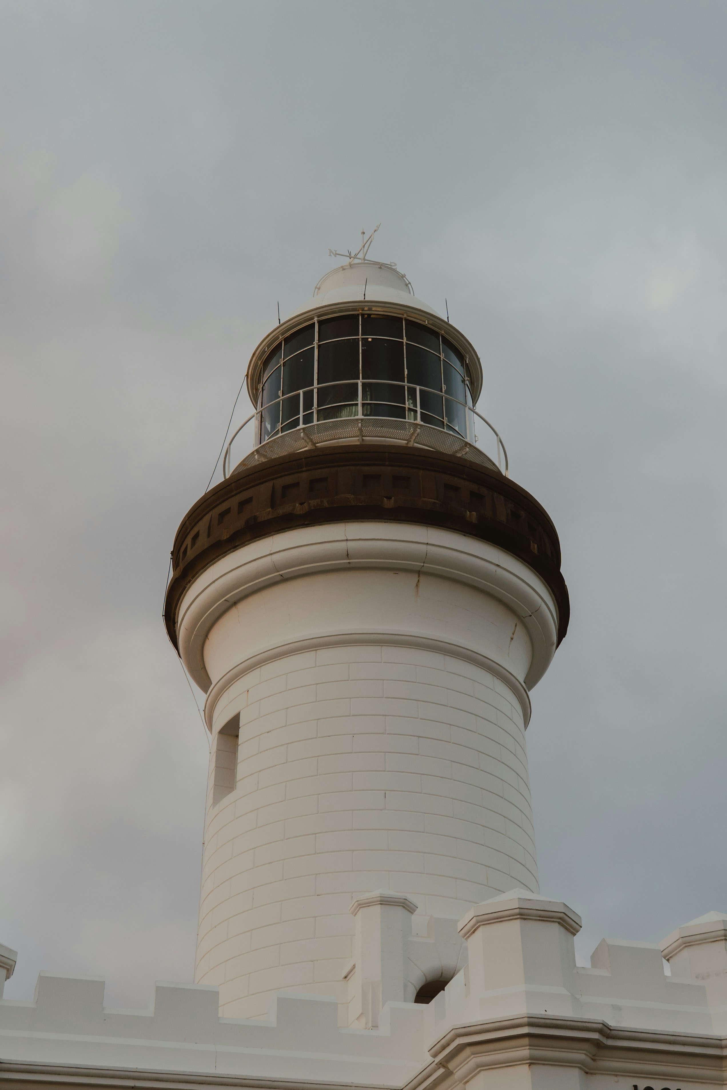 White lighthouse stands tall against a cloudy sky.