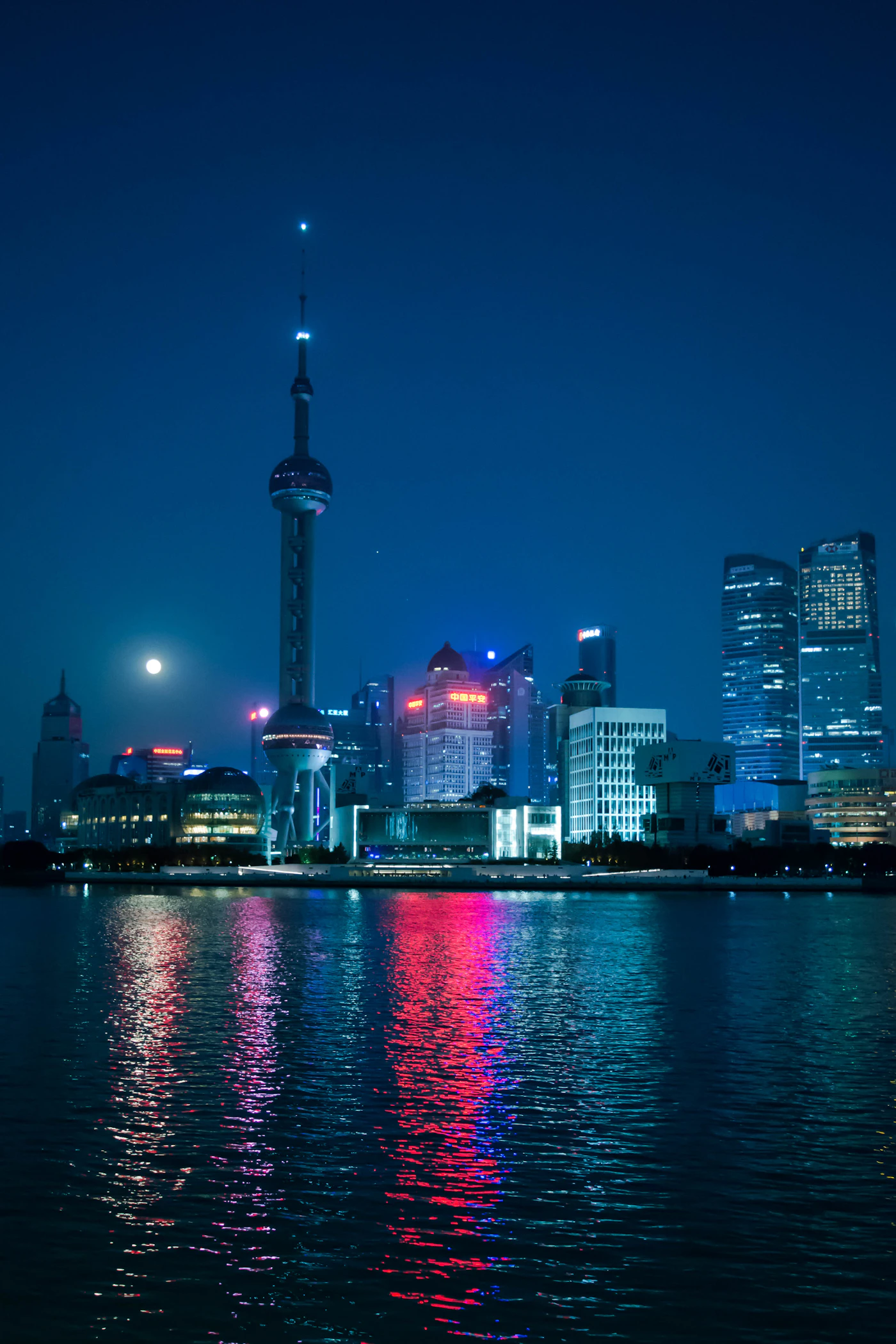 El Bund de Shanghái de noche con los rascacielos de Pudong reflejados en el río Huangpu