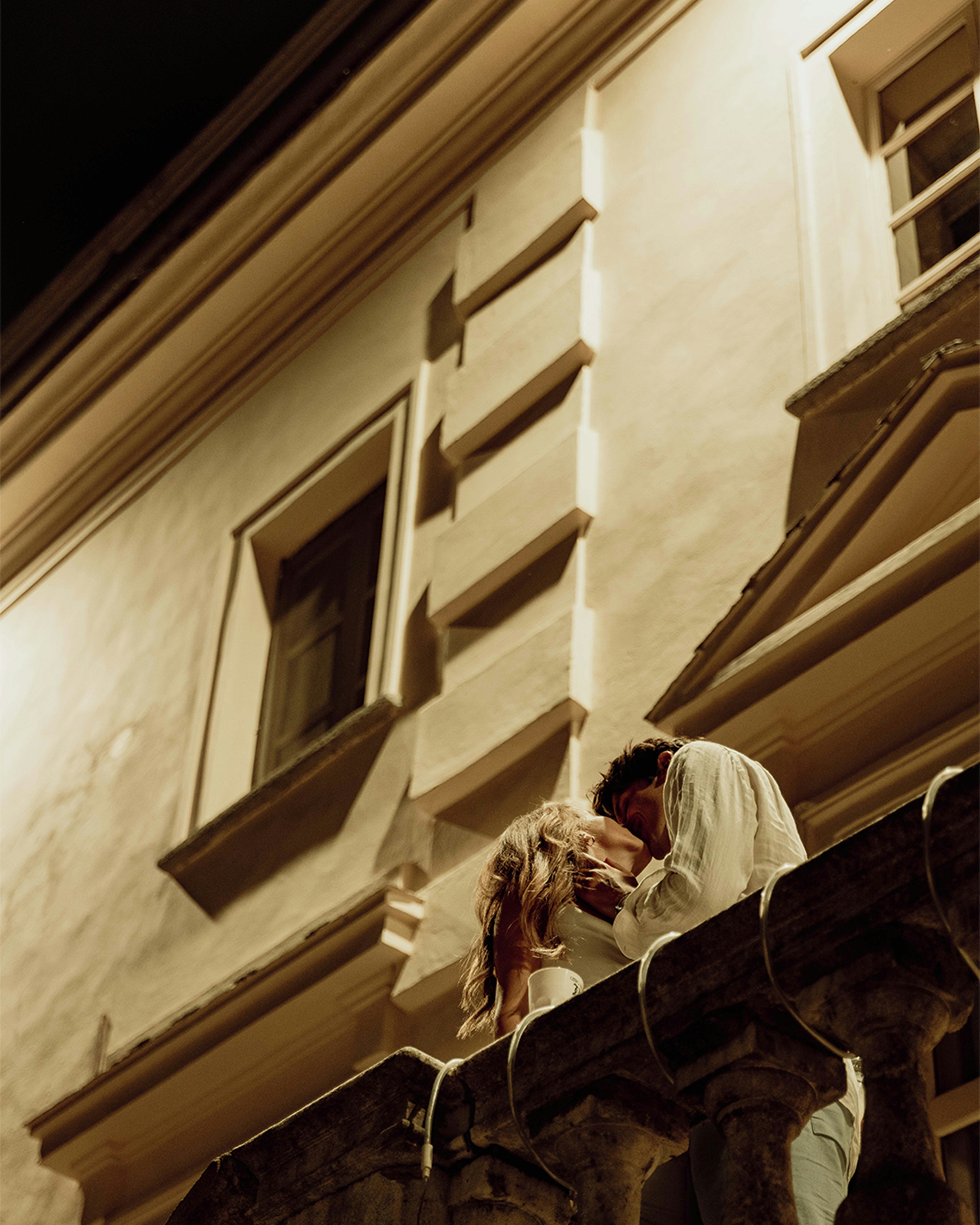 Couple kissing on a balcony at night