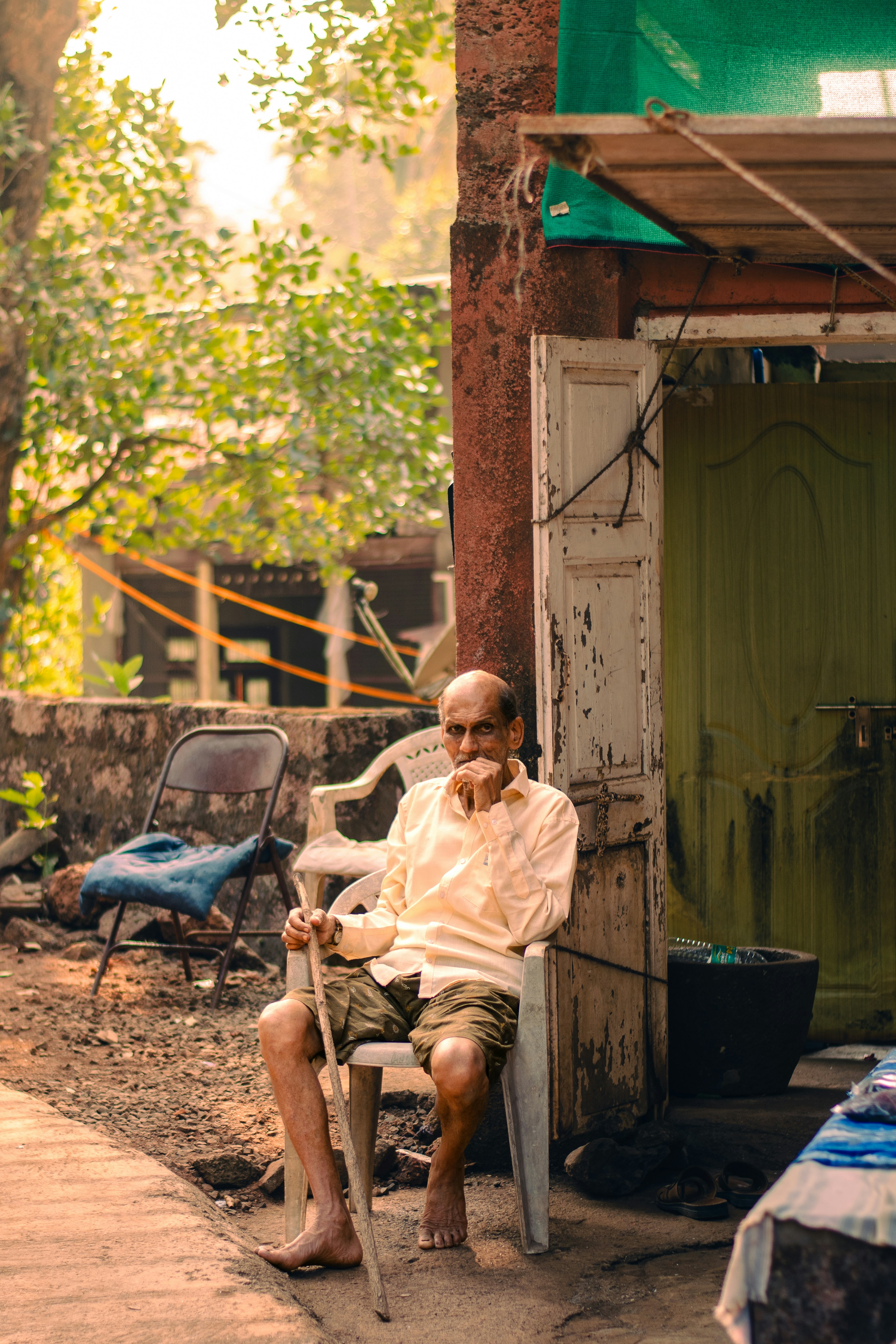 An elderly man sits outdoors, contemplating.