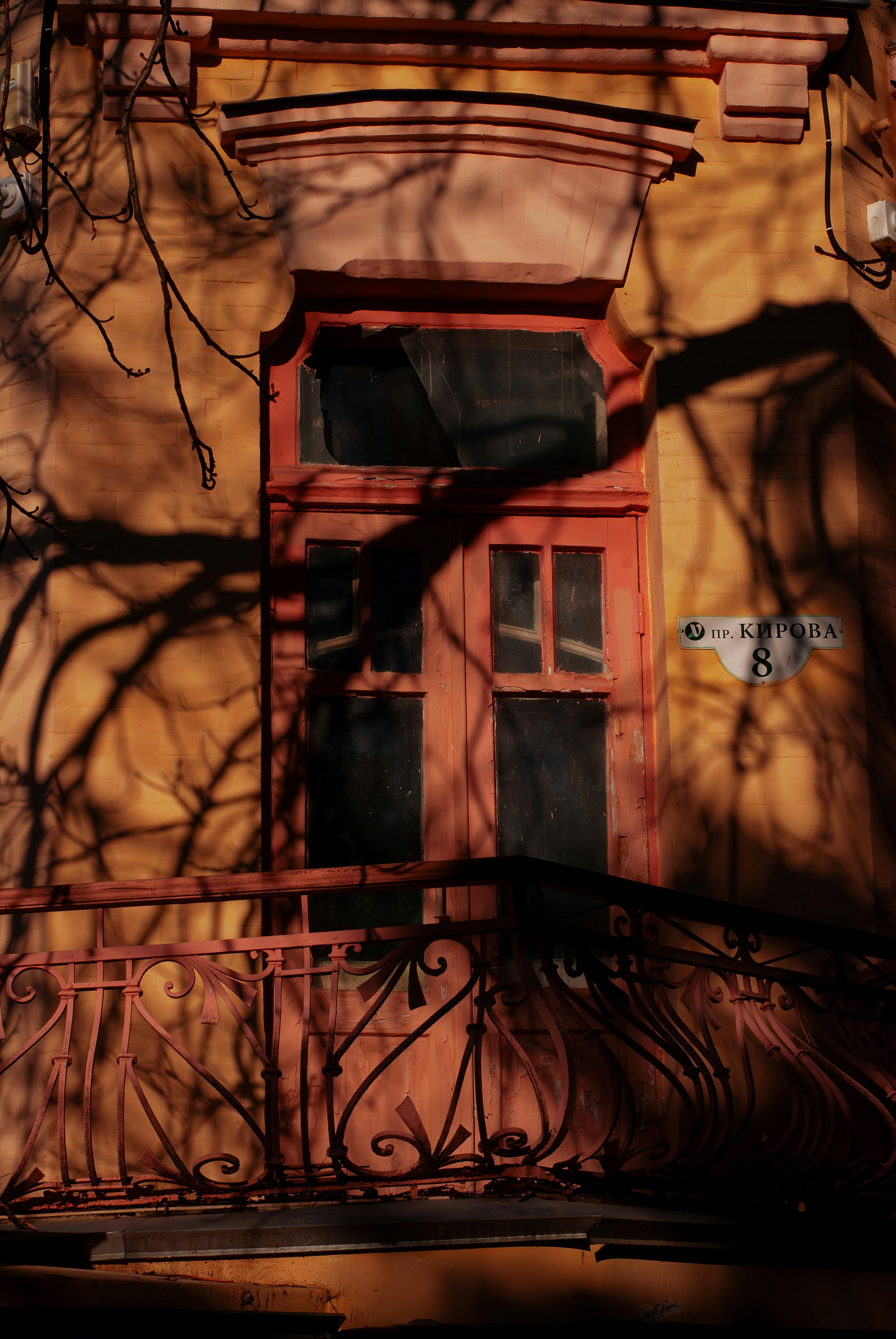Shadows fall across an old building with a balcony.