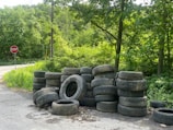 A pile of used tires beside a road.