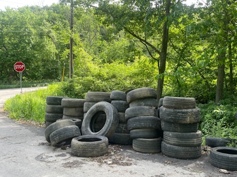 A pile of used tires beside a road.