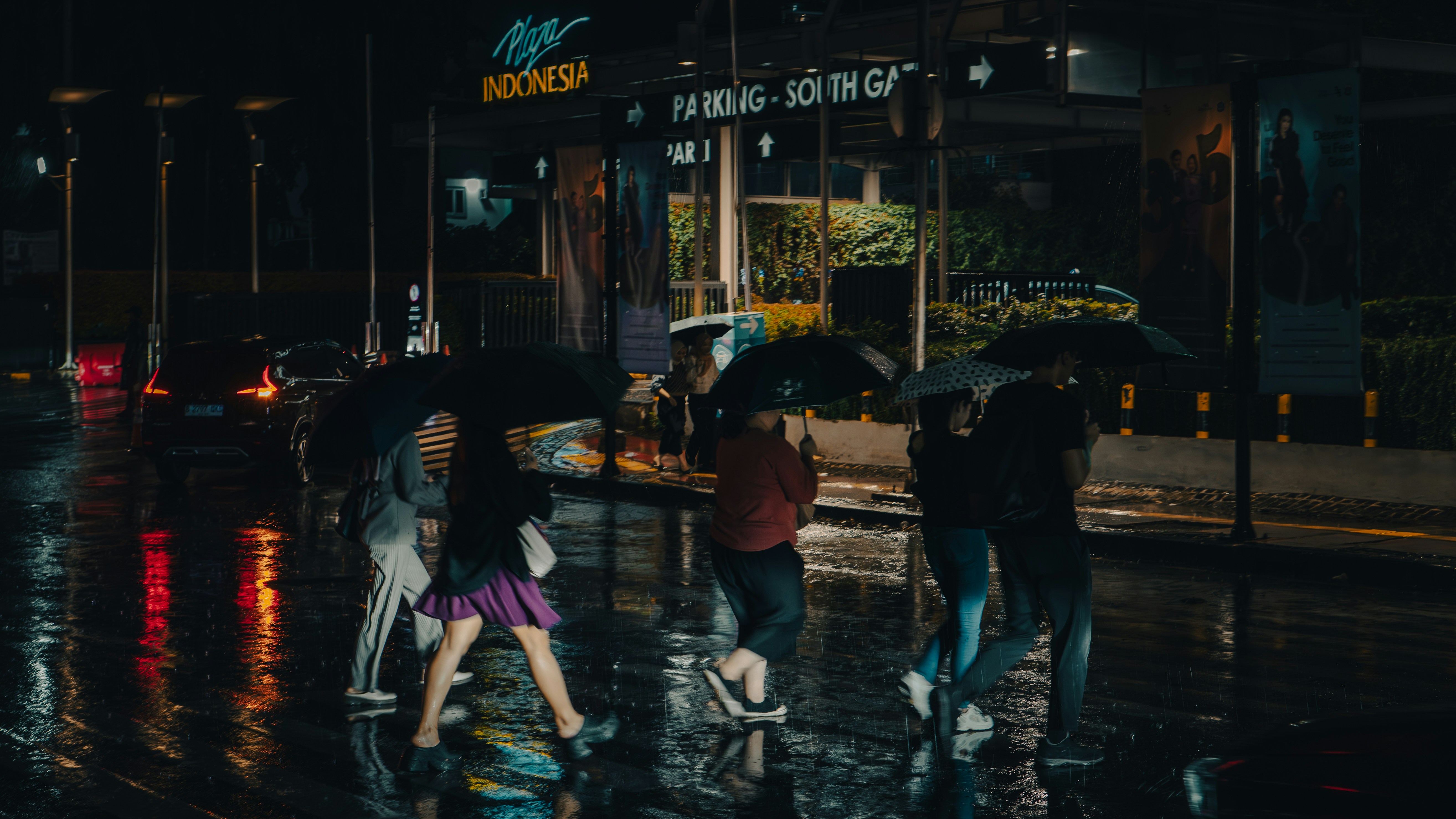 People walk across a street in the rain.